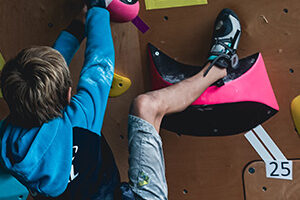 Niño de espaldas escalando en un rocódromo